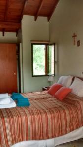 een slaapkamer met een bed met rode kussens en een raam bij Chalets Andalgala in Merlo