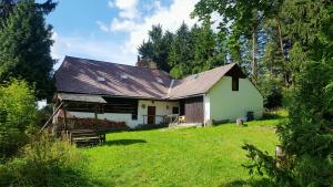 ein Haus mit einem Metalldach auf einem grünen Hof in der Unterkunft Malebná chalupa u Javorníku na Šumavě in Vacov