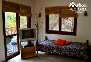 a bedroom with a tv and a bed with orange pillows at Victoria Cabañas in Tigre