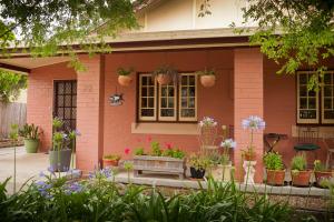 una casa rosa con piante in vaso davanti di Taree Apartment a Taree