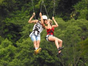 two girls are riding on a rope swing at Pousada Alvorada Brotas - e agendamento das atividades turísticas in Brotas