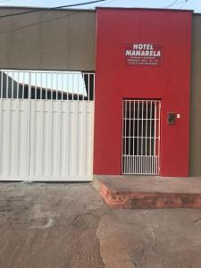 a red building with a white fence and a door at Hotel Manarela in Imperatriz
