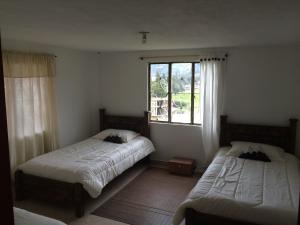 a bedroom with two beds and a window at Hostal Casa Lantana in Suesca