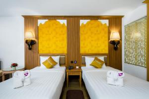 Habitación de hotel con 2 camas con sábanas blancas en Aiyara Palace, en Norte de Pattaya