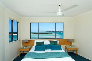 1 dormitorio con 1 cama grande con almohadas azules en BreakFree Grand Pacific, en Caloundra