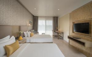 um quarto de hotel com duas camas e uma televisão de ecrã plano em Kabir Hotel & Spa em Vadodara