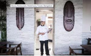 un chef parado en la puerta de un restaurante en Ivory Tower en Bangalore