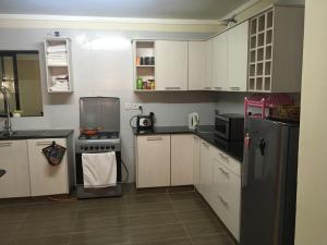 een keuken met witte kasten en een zwarte koelkast bij Casa ozone in Nairobi