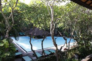 a swimming pool in the middle of some trees at Hotel Puri Bambu in Jimbaran