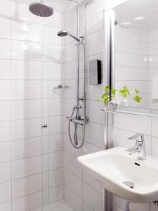 a white bathroom with a shower and a sink at Clarion Collection Hotel Smedjan in Sandviken