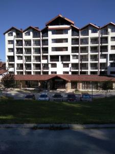 a large building with cars parked in a parking lot at Borovest Garden. in Borovets