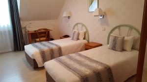 a hotel room with two beds and a desk at Logis Hôtel Restaurant Beau Rivage in Saint-Baudelle