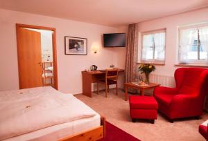 DrolshagenにあるHaus Dumicketalのベッド、デスク、赤い椅子が備わるホテルルームです。