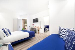 a white and blue bedroom with a bed and a desk at Sirocco Suites in Sant'Agnello