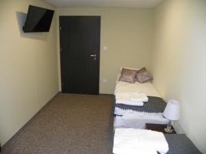 a room with two beds and a television and a door at Gościniec Młyn in Chodecz