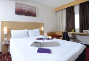 ibis Seef Manama في المنامة: غرفة في الفندق مع سرير مع لاب توب عليه