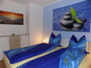 a bedroom with a bed with blue sheets and a painting at Ferienwohnung Rothe in Dippoldiswalde