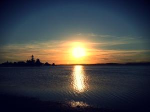 a sun setting over a large body of water at Aquarius Motel in Belmont