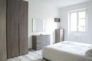 a white bedroom with a bed and a dresser at Mi Suzzani in Milan