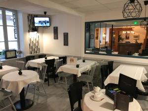 a restaurant with white tables and chairs and a mirror at Hôtel L'Estran in Trouville-sur-Mer