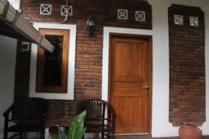 a brick house with a wooden door and two chairs at Rumah Pathuk Syariah Homestay in Yogyakarta
