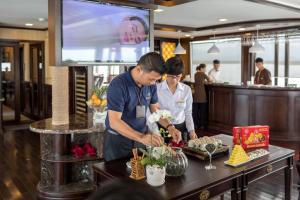 two people preparing food at a buffet in a restaurant at Orchid Trendy Cruise in Ha Long