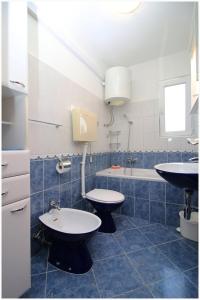 a bathroom with two toilets and a sink and a tub at Apartments HULJEV in Primošten