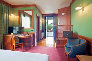 una camera d'albergo con letto, scrivania e specchio di Arosio Hotel ad Arosio