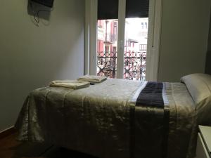 a bed with two towels on it in front of a window at Pensión La Bilbaina - Albergue Logroño in Logroño