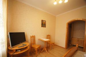 Una sala de estar con un televisor y una mesa con sillas. en Zirka Karpat, en Yasinya