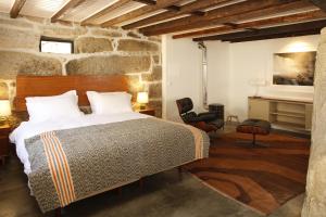 a bedroom with a bed and a stone wall at Casa Estrela Loft in Juncais
