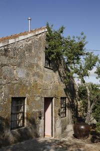 an old stone building with a door and a tree at Casa Estrela Loft in Juncais +2 photos