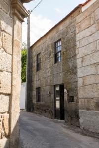 an old stone building with a door in a street at Casa Estrela Loft in Juncais