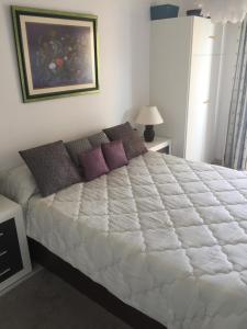 エステポナにあるBellavista del marのベッドルーム(紫色の枕が付いた大きな白いベッド付)