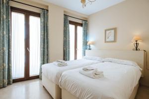 Habitación blanca con 2 camas y toallas. en Bright and beautiful- VTV- Conde de Torrejón 10 en Sevilla