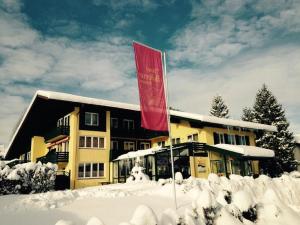 ein Gebäude mit einer roten Flagge im Schnee in der Unterkunft Hotel-Restaurant Bellevue in Ruhpolding