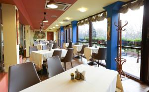 a restaurant with white tables and chairs and windows at Smėlynė in Panevėžys
