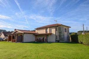 a house with a green lawn in front of it at Casona de Llanorrozo Apartamentos Rurales in Oviñana