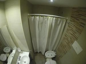 
a bathroom with a toilet, sink, and shower stall at Hotel Catedral in Mar del Plata
