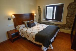 a bedroom with a large bed and a window at Casona de Llanorrozo Apartamentos Rurales in Oviñana