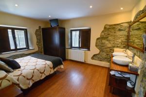 a bedroom with a bed and a sink and a stone wall at Casona de Llanorrozo Apartamentos Rurales in Oviñana