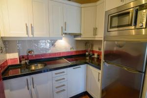 a kitchen with white cabinets and a stainless steel refrigerator at Casona de Llanorrozo Apartamentos Rurales in Oviñana