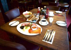 a wooden table with a plate of food on it at Wayford Bridge Inn Hotel in Stalham