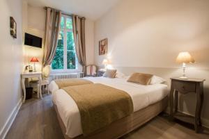 Hotel Val De Loire في تور: غرفة نوم بسرير ومكتب ونافذة