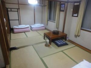 Habitación con 2 camas y mesa. en Kasuga Ryokan en Hiroshima