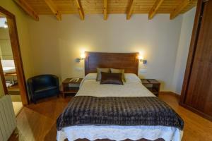 a bedroom with a large bed and a chair at Casona de Llanorrozo Apartamentos Rurales in Oviñana