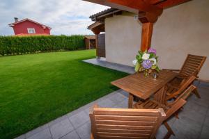 a wooden table and chairs on a patio with a yard at Casona de Llanorrozo Apartamentos Rurales in Oviñana