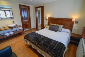 a bedroom with a large bed and a bathroom at Casona de Llanorrozo Apartamentos Rurales in Oviñana