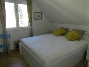 um quarto com uma grande cama branca com almofadas amarelas em Ferienwohnung Ferienhaus Hohwachter Bucht Ostsee DSL WLAN em Hohwacht