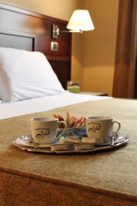 two coffee cups on a tray on a bed at Panorama Hotel in Syracuse